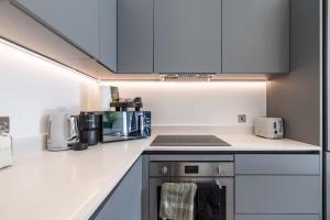 a kitchen with white cabinets and a stove top oven at Elegant apartment/2 in Buckinghamshire