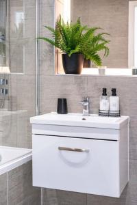 ein Badezimmer mit einem weißen Waschbecken und einer Pflanze in der Unterkunft Elegant apartment/2 in Buckinghamshire
