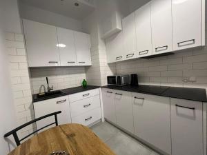 a kitchen with white cabinets and a wooden table at Heart of Old Town / Floriańska 19 in Krakow