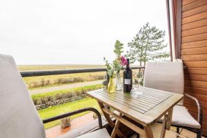 un tavolo con una bottiglia di vino e fiori sul balcone di Heefwai-2-W5 a Morsum
