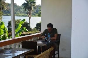 Ein Mann, der an einem Tisch in einem Restaurant sitzt. in der Unterkunft Lakeshore Bed and Breakfast in Entebbe