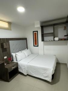 1 dormitorio con 1 cama blanca grande y mesita de noche en Hotel Juan Pablo 2, en Ríohacha
