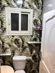 a bathroom with a toilet with a tropical wallpaper at شقة فندقية 108 in Cairo