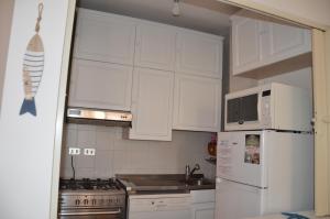a kitchen with white cabinets and a white refrigerator at Appartamenti Fronte Mare Fertilia FAHO-GAV01-GAV02 in Fertilia
