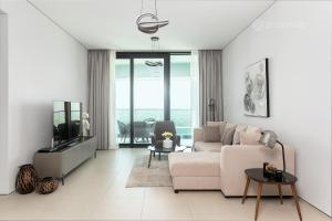 The Address Beach Residences - 2BR & Private Beach في دبي: غرفة معيشة بيضاء مع أريكة وتلفزيون