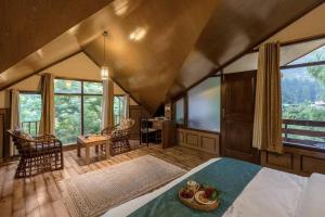 una camera con letto, tavolo e sedie di Bear Creek: Luxury 2BHK Cottage near Mall Road a Manāli