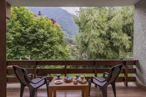 a table and chairs on a balcony with a view at Bear Creek: Luxury 2BHK Cottage near Mall Road in Manāli