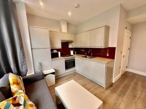 a living room with a couch and a kitchen at Upminster Bridge Station Excel House in Hornchurch
