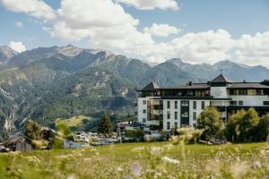 a building on a hill with mountains in the background at Schlosshotel Fiss in Fiss