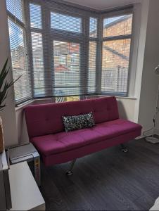 a purple couch in a living room with windows at Tottenham Stadium Rooms 1 in London