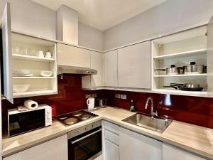 a kitchen with white cabinets and a sink and a microwave at Upminster Bridge Station Excel House in Hornchurch