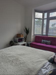 a bedroom with a bed and a purple couch at Tottenham Stadium Rooms 1 in London