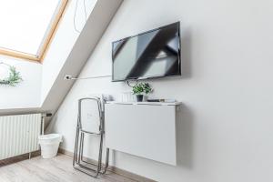 a flat screen tv on a wall in a living room at 10-Min Walk to Hauptbahnhof, Cozy Private Rooms with AC, TV & WIFI in Vienna