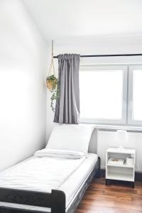 Bett in einem weißen Zimmer mit Fenster in der Unterkunft Hostel L44 in Nowy Targ