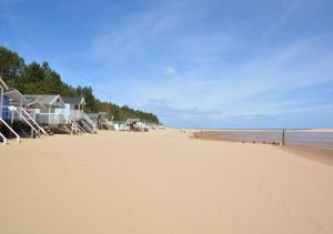 a sandy beach with houses and the ocean at South Flat in Wells next the Sea