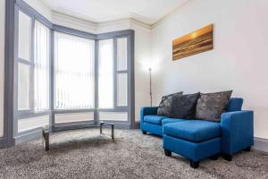 a living room with a blue couch and windows at Guest Homes - Bambro Flat in Sunderland
