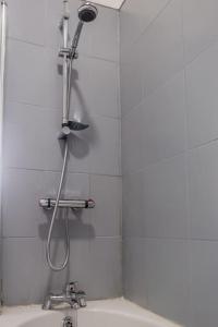 a shower in a white tiled bathroom with a sink at Guest Homes - Bambro Flat in Sunderland