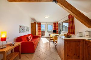 a living room with a red couch and a table at Gasserhof Ferienwohnung Morgenduft in Caines