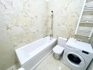 y baño con bañera, aseo y lavadora. en Central Adress CD22, en Bucarest