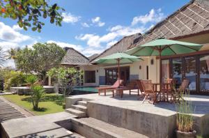 a house with a patio with tables and umbrellas at Star Sand Beach Resort in Sekotong