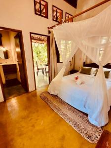 1 dormitorio con cama blanca y mosquitera en Pousada Big Bambu, en Trancoso