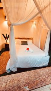 - un lit blanc avec une fleur rouge dans l'établissement Pousada Big Bambu, à Trancoso