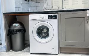 a washing machine and a trash can in a kitchen at Stylish 3 bed flat with Garden in London