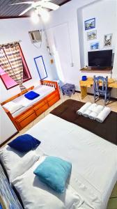 a room with two beds and a tv at Pousada Lira Praieira Paraty in Paraty