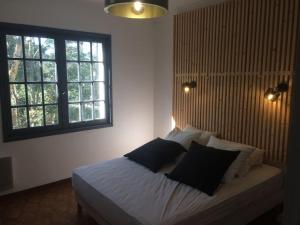 um quarto com uma cama com lençóis brancos e almofadas pretas em Villa 16 personnes, plage à 300m em Labenne