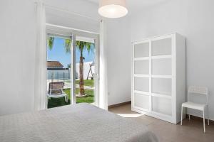 カディスにあるCasa Pepi Solo Familiasの白いベッドルーム(ベッド1台付)、ガラスのスライドドアが備わります。 +21枚の写真