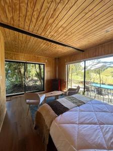a bedroom with a large bed and a large window at Cabaña en el bosque Chiloé in Curaco de Velez