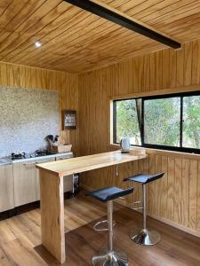 a kitchen with a counter and stools in a room at Cabaña en el bosque Chiloé in Curaco de Velez
