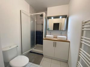 uma casa de banho com um chuveiro, 2 lavatórios e um WC. em Superbe Appartement centre Sautron em Sautron