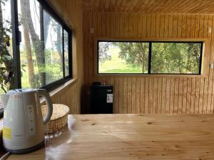 a table with a coffee mug sitting on top of a room with windows at Cabaña en el bosque Chiloé in Curaco de Velez