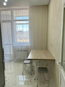 uma mesa e duas cadeiras num quarto com uma janela em Altyn Dala em Taldykolʼ
