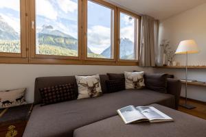 a living room with a couch with a book on it at Chasa Vi in Scuol