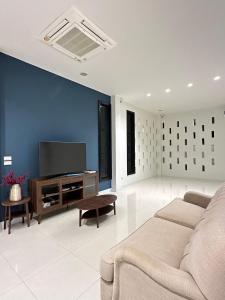 ein Wohnzimmer mit einem Sofa und einem Flachbild-TV in der Unterkunft House40 - MRT Ratchadaphisek in Bangkok