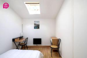 een slaapkamer met een bed, een bureau en een televisie bij L'Oasis by iZiLi - Proche Hypercentre - Paisible in Niort