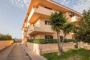 een gebouw met een palmboom ervoor bij Olbia Oasis Apartment with Two Balconies! in Olbia