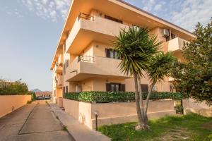 um edifício com uma palmeira em frente em Olbia Oasis Apartment with Two Balconies! em Olbia