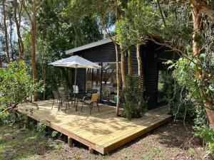 a wooden deck with a table and an umbrella at Cabaña en el bosque Chiloé in Curaco de Velez