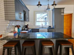 a kitchen with a counter with stools and a sink at The Old School House - Parking & Close to City in Salisbury