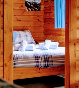 ein Schlafzimmer mit einem Bett in einem Blockhaus in der Unterkunft Loch Insh Chalets Ltd in Kincraig