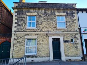 een oud bakstenen gebouw met twee ramen en een deur bij The Old School House - Parking & Close to City in Salisbury