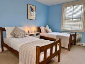 two beds in a room with blue walls at The Old School House - Parking & Close to City in Salisbury