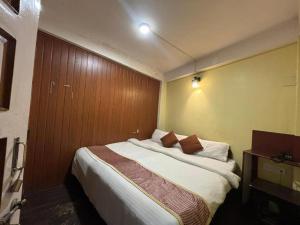 ein Schlafzimmer mit einem Bett mit einer Holzwand in der Unterkunft HOTEL PURNI DARJEELING in Darjeeling