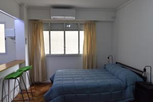 a bedroom with a blue bed in front of a window at Belgrano Cozy Suite in Buenos Aires