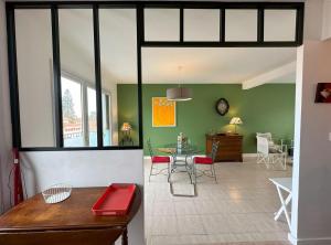 een woonkamer met groene muren en een tafel en stoelen bij Jules in Dax