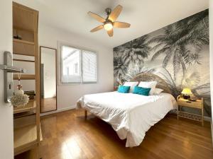 een slaapkamer met een bed met een schilderij van palmbomen bij Jules in Dax