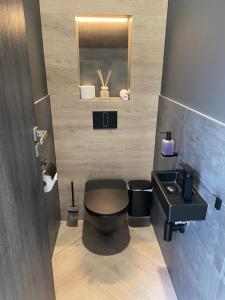 a bathroom with a black toilet and a sink at M26 Prémium apartmanok in Tihany